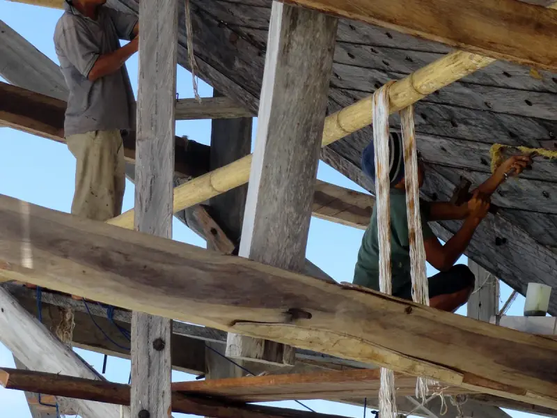 A shipwright working on the frames of a wooden phinisi hull at Bira Beach, South Sulawesi